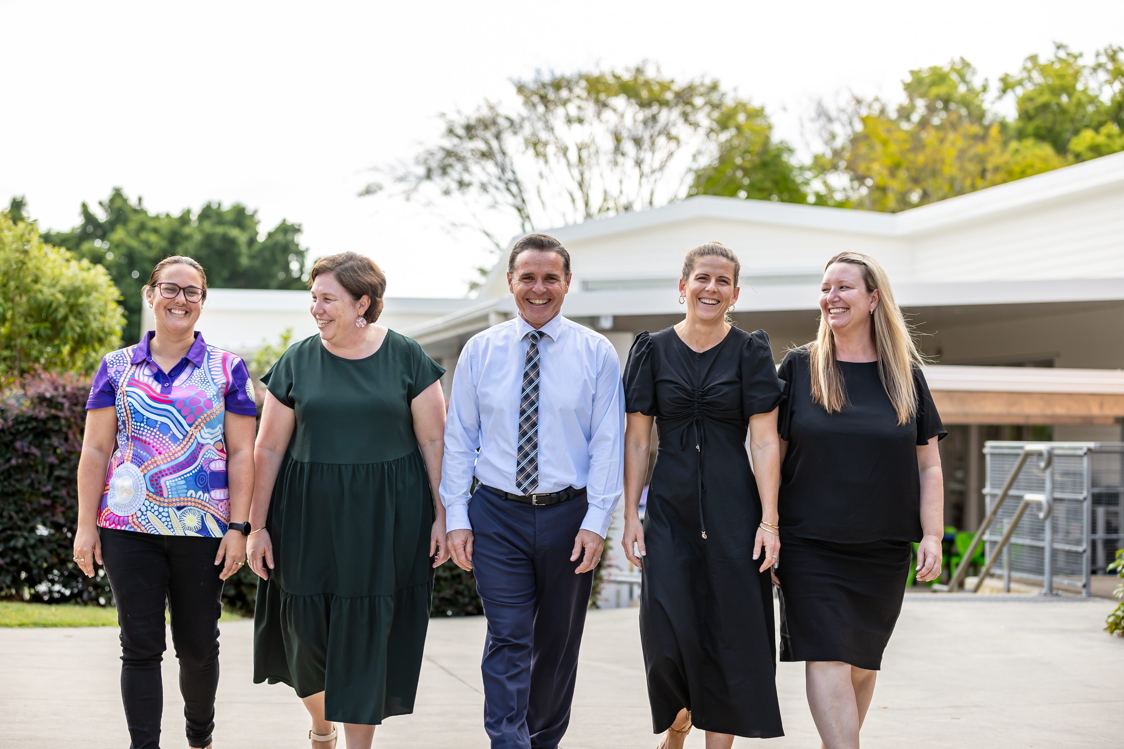 Five adults walking in a line outside.