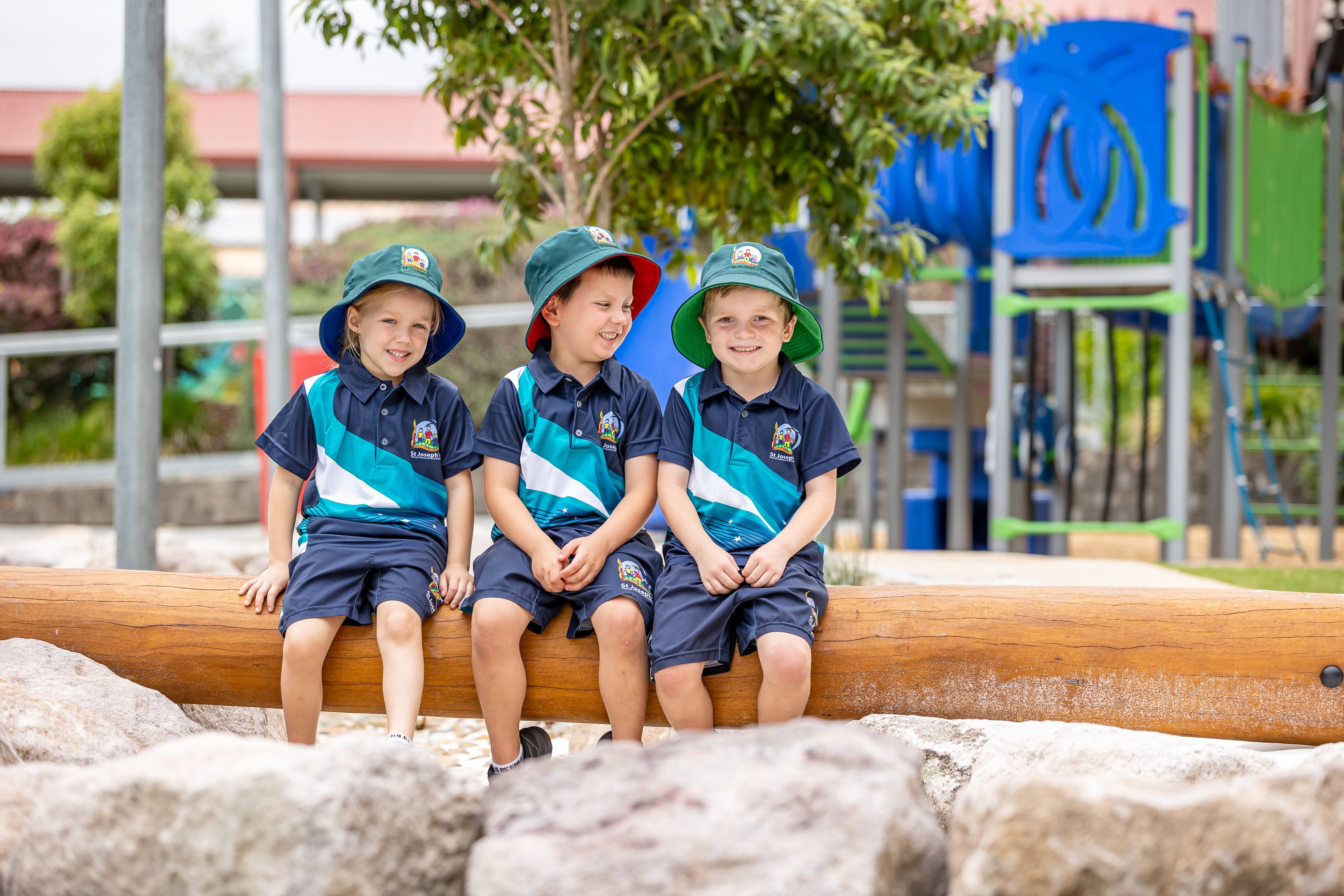 3 children sitting on a log