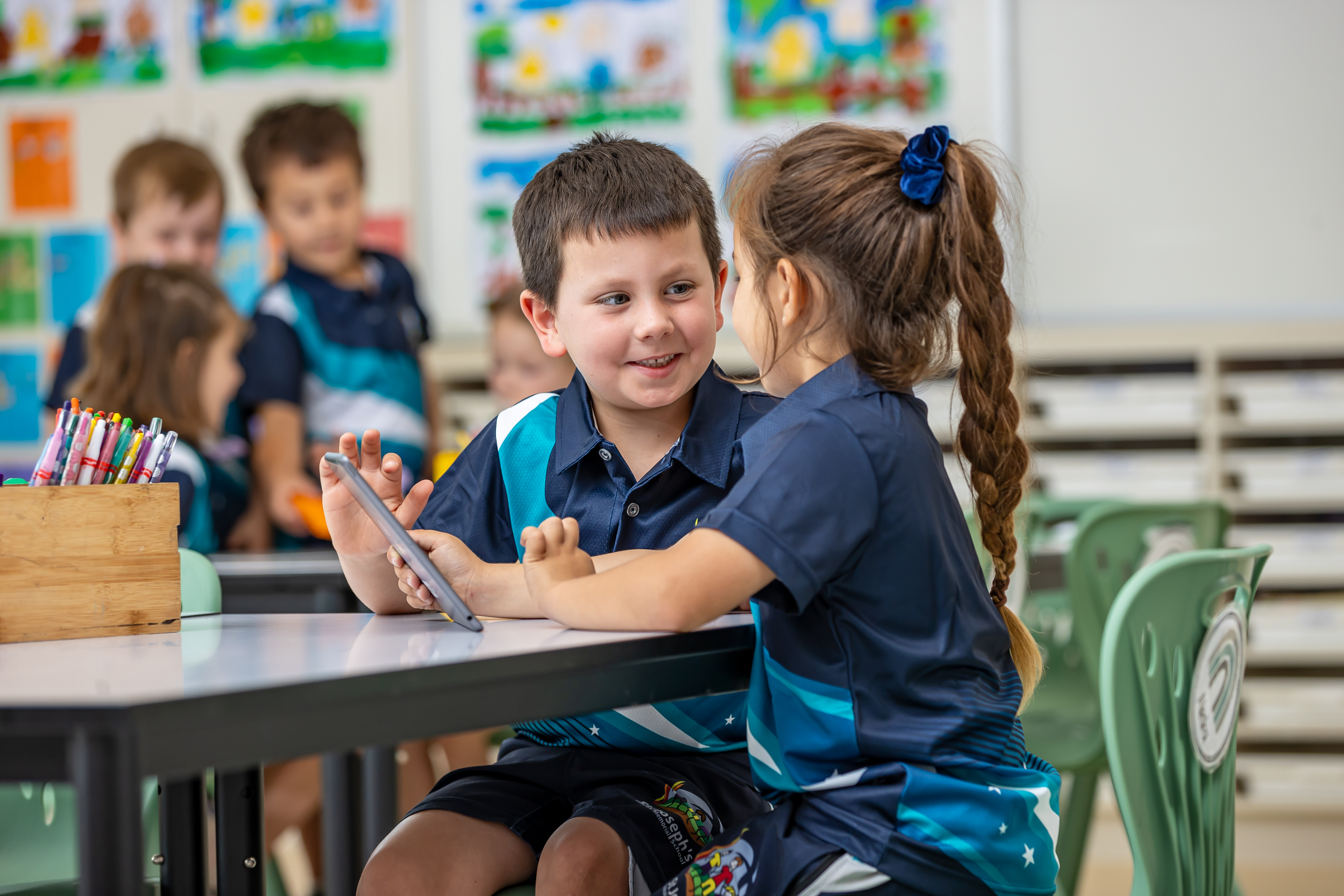 Two students using an Ipad in a classroom.
